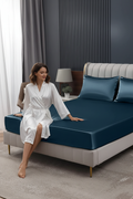 Deep sea blue satin fitted sheet with person in luxury bedroom