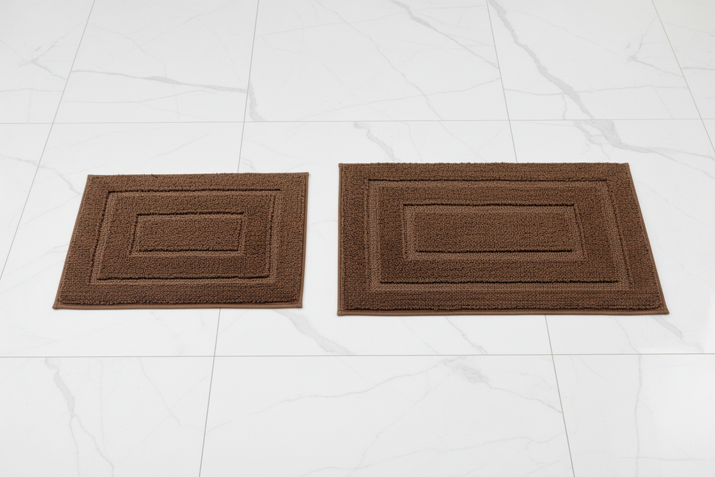 Brown bath rug set overhead shot on white marble bathroom tiles