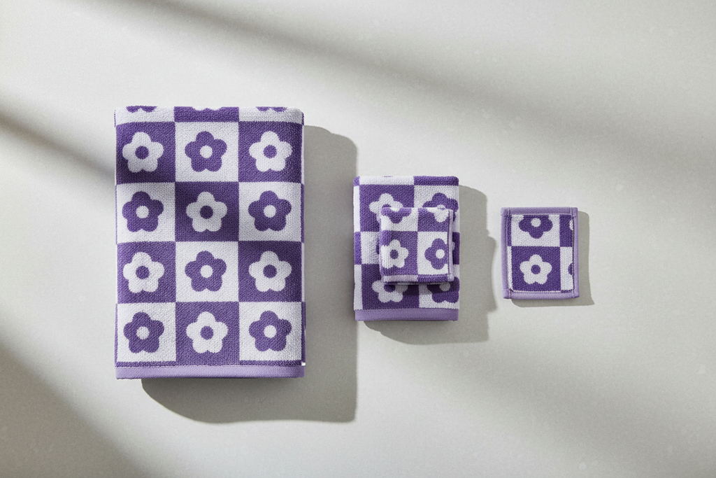 Purple checkerboard floral coral fleece towel set flat lay on light grey surface