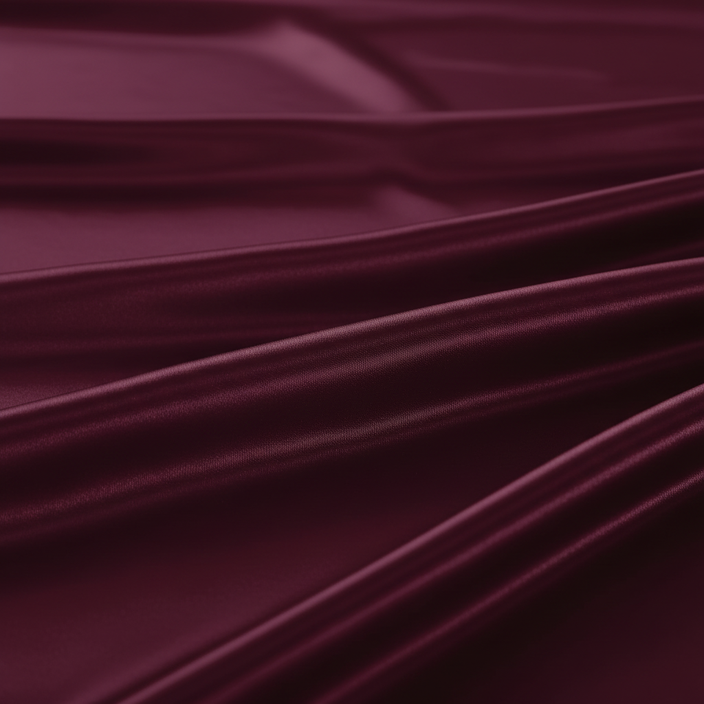 Close-up of burgundy satin fabric showing silky smooth sheen and luxurious texture