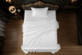 Top-down aerial view of white silky satin sheet set on single bed